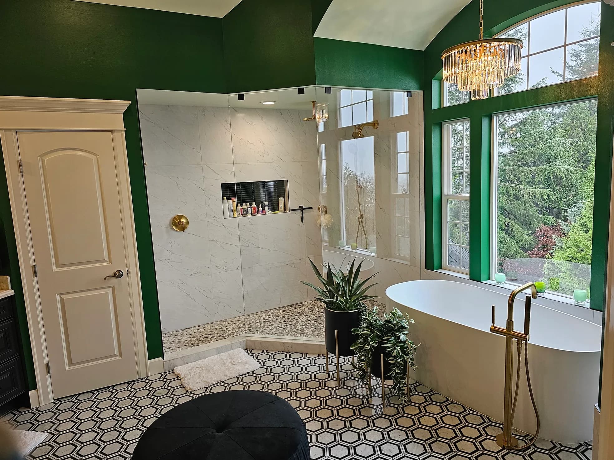Emerald master bathroom from second angle showing frameless glass shower entrance with pebble floor and gold hardware