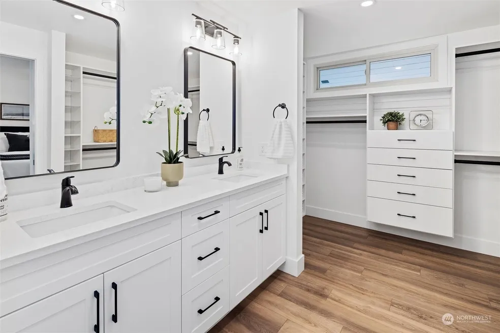 Master bathroom with white double vanity, quartz countertop, black-framed mirrors, matte black fixtures, and walk-in closet visible adjacent