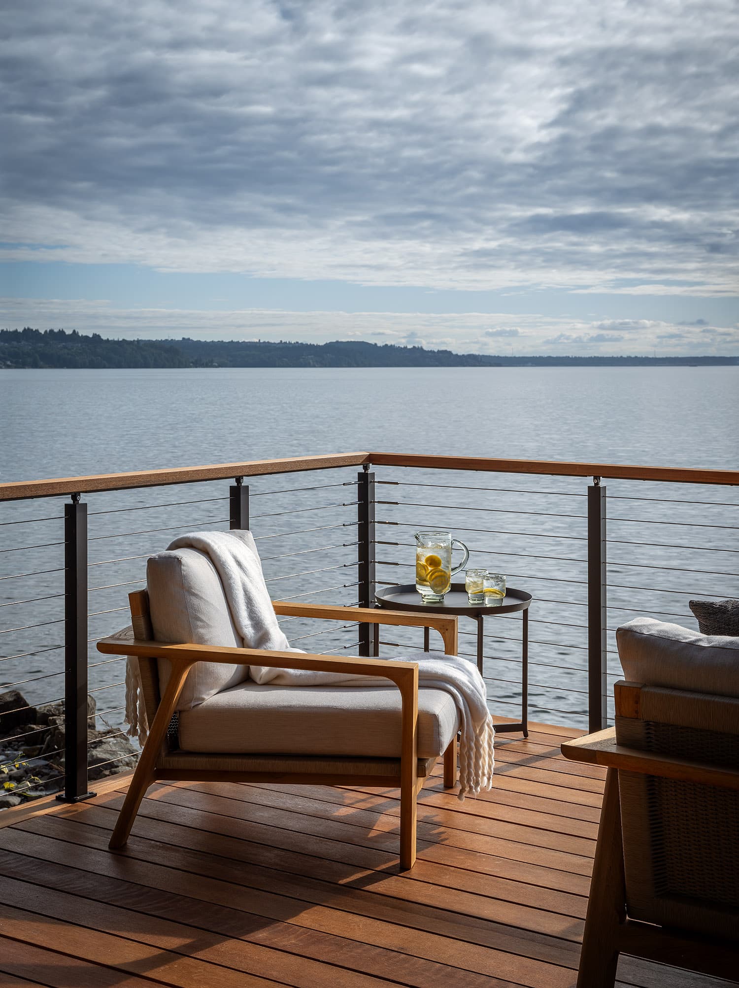 Waterfront deck with cable railing, teak furniture, and Puget Sound view