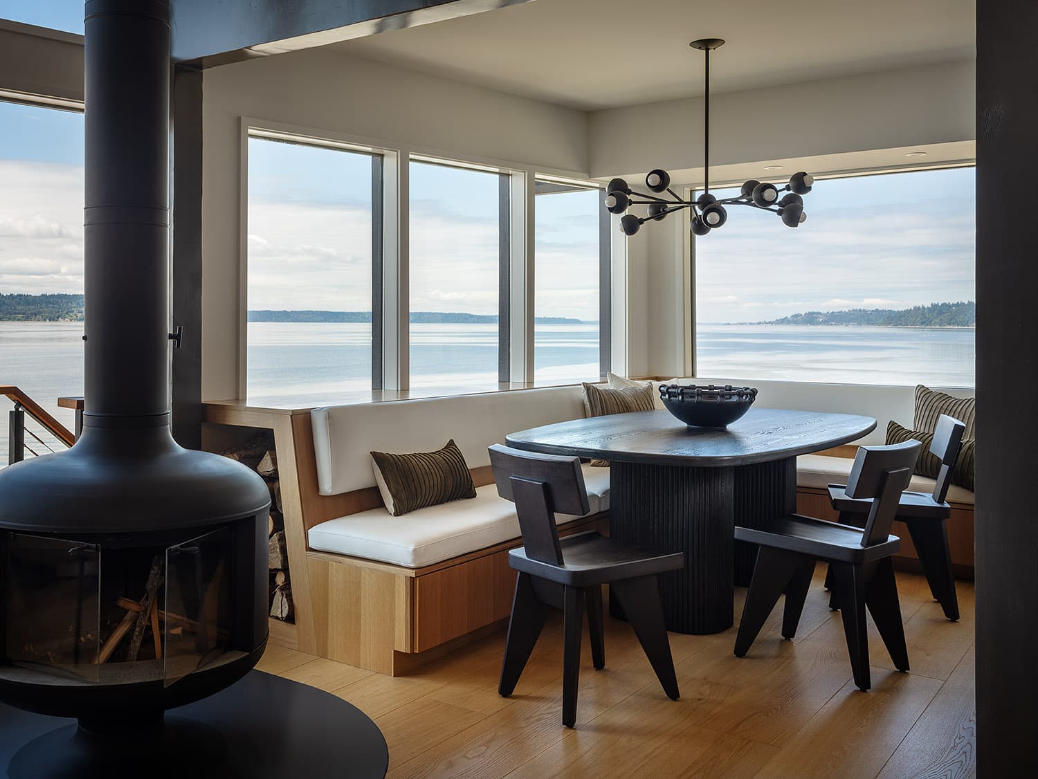 Dining nook with built-in banquette, freestanding fireplace, and waterfront view